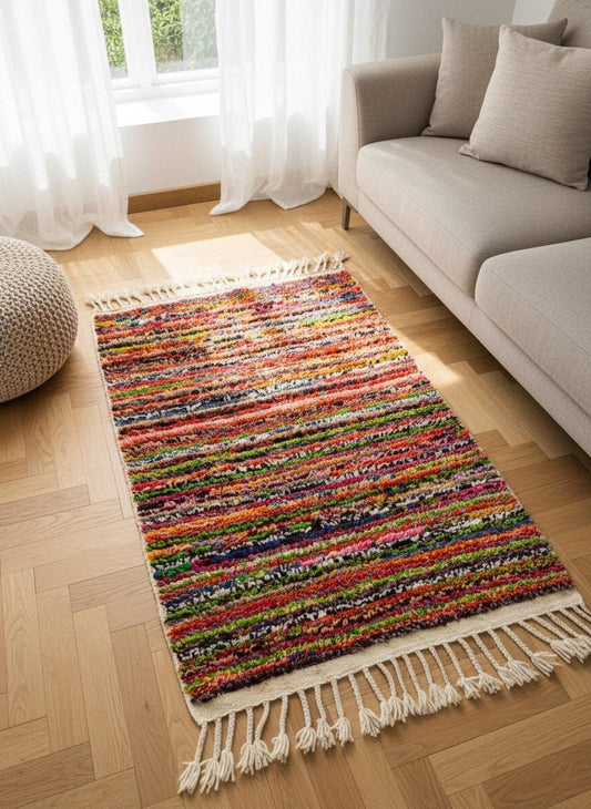 Small Moroccan rag rug with multicolor stripes near sofa