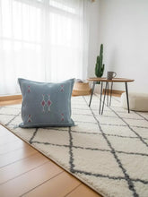 Blue Moroccan cactus silk pillow styled on cream Berber rug with coffee table
