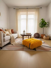 Bright yellow Moroccan pouf styled as a floor cushion in a cozy living space.