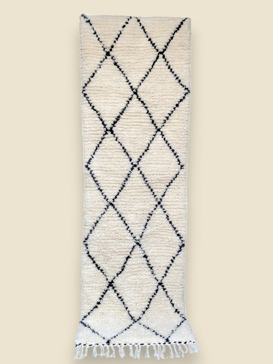 Handwoven Aicha Moroccan rug with black diamond pattern on ivory wool, finished with white fringes.