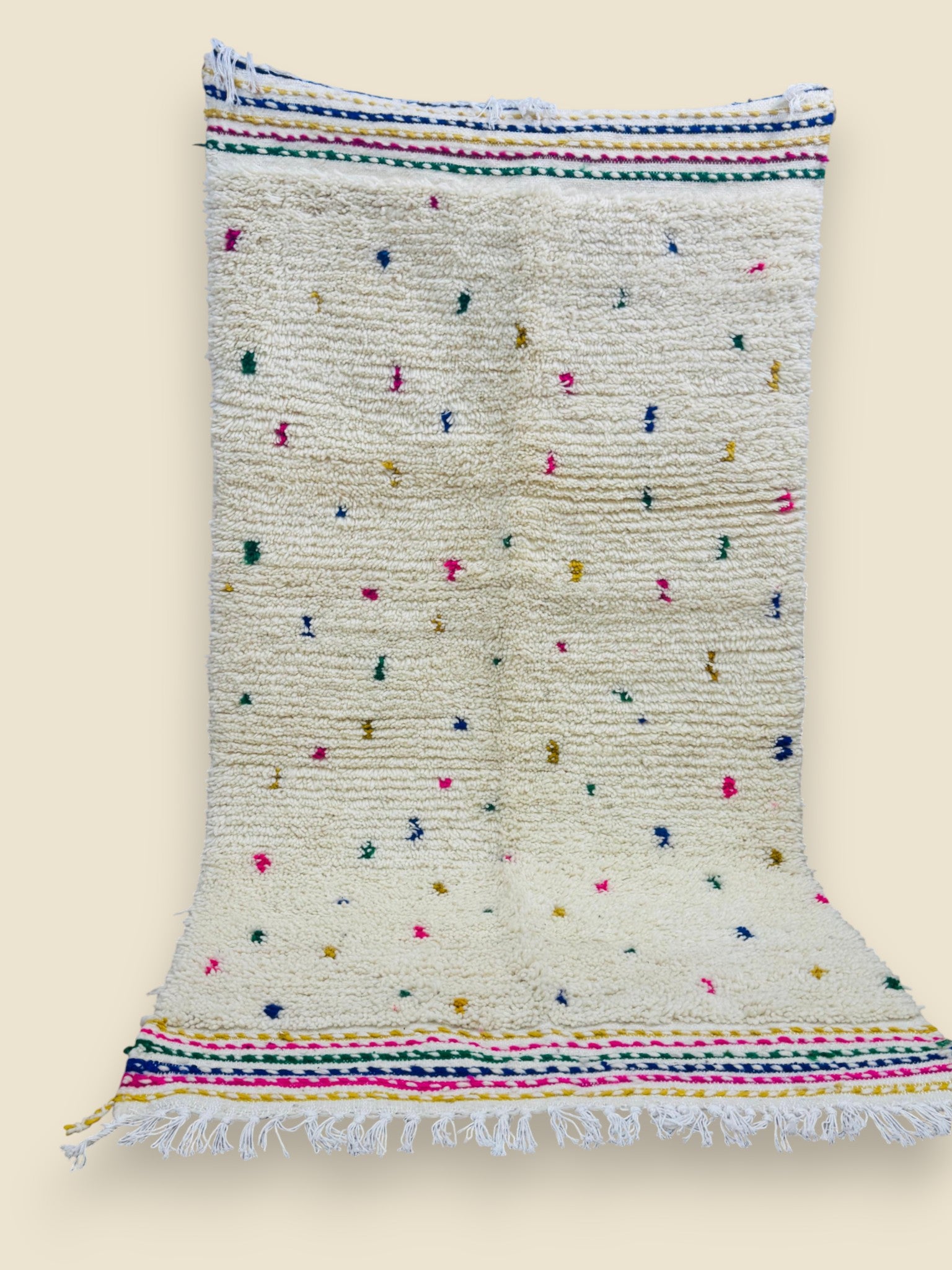 Flatwoven rug with scattered colorful tufts and tasseled ends.