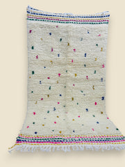 Flatwoven rug with scattered colorful tufts and tasseled ends.