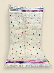 Ivory Berber rug with rainbow stripes and hand-knotted fringe.