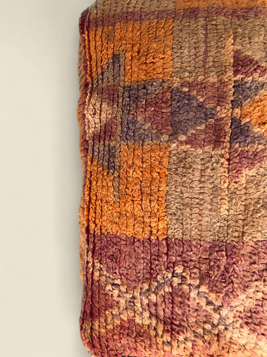 Rust and orange Moroccan wool pouffe used as an ottoman or seat