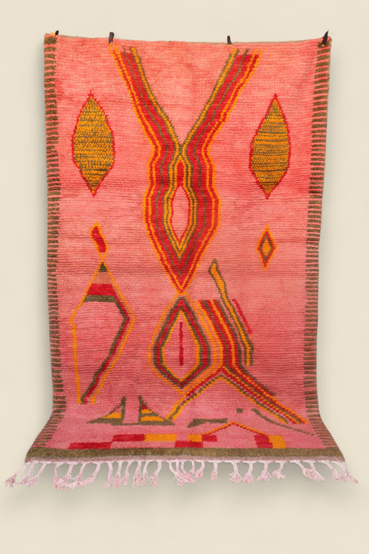 Full view of the Limra Moroccan rug with geometric tribal motifs on a pink background