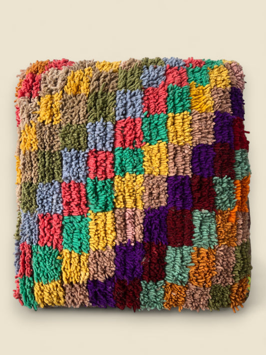 Top view of multicolor Moroccan pouffe with hand-knotted wool squares