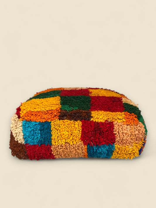 Side profile of Tirga pouffe showing textured wool in vibrant Berber colors