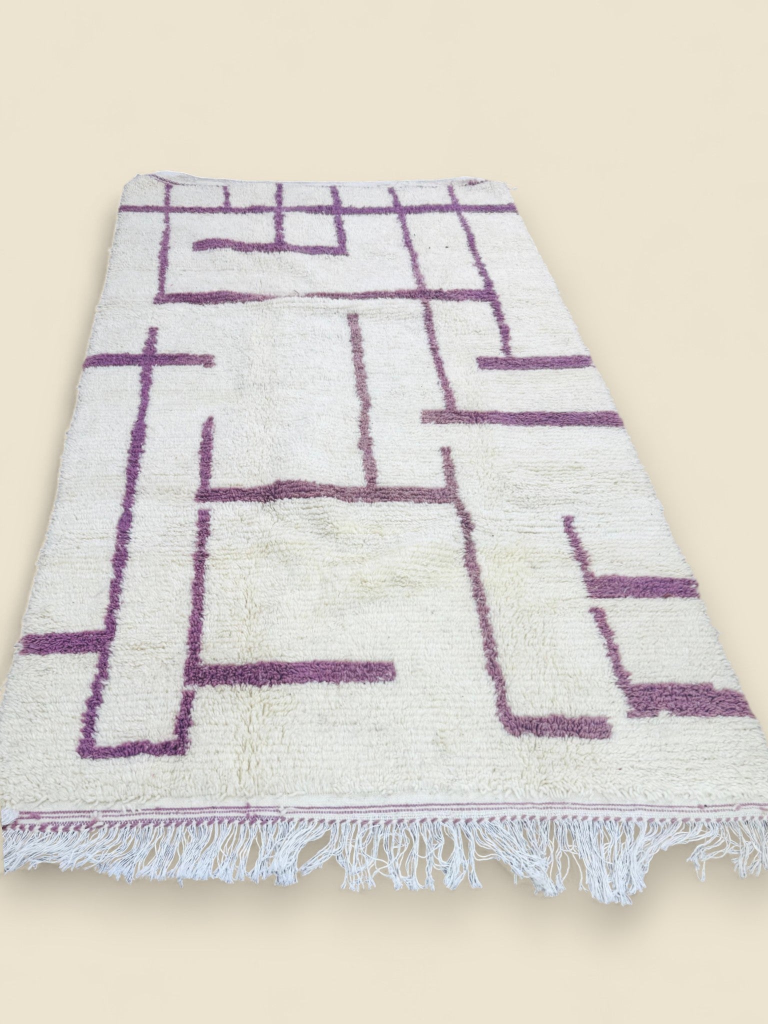 Handwoven Berber carpet displayed on wooden floor with mauve pattern