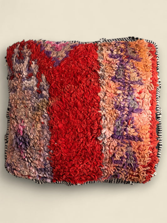 Colorful Moroccan pouffe with red center and multicolor wool texture, handmade and square-shaped.