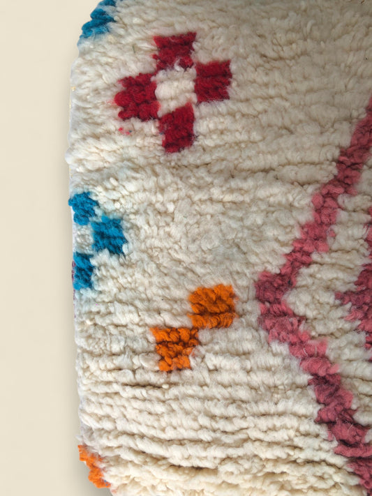 Close-up of red, orange, and blue geometric wool motifs on the Tizerzit pouffe