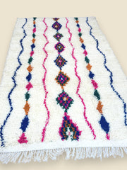 Handmade Tiziriwen Moroccan rug with colorful diamond patterns on ivory wool