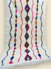 Handwoven Moroccan Tiziriwen rug displayed vertically against wall