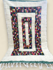 Wool Moroccan rug with colorful geometric blocks and fringed edges.