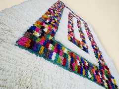 Colorful Moroccan Berber rug with geometric pattern on cream wool.
