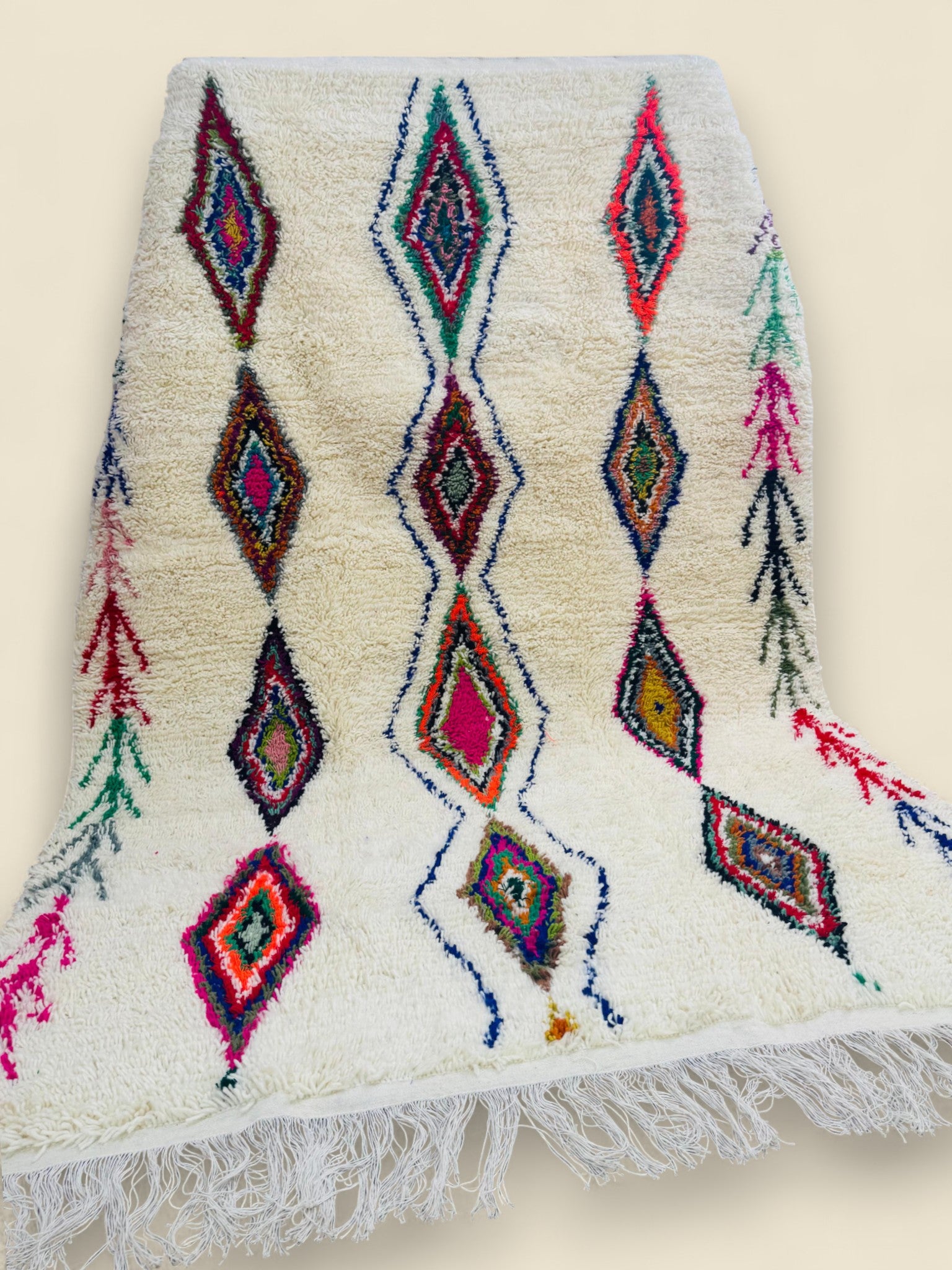 Handwoven Moroccan Berber rug with fringed edges and diamond symbols
