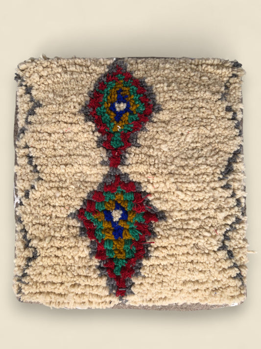 Top view of Yanna Moroccan Berber pouffe with colorful diamond motifs on cream wool