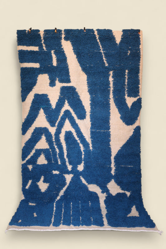 Full view of Ziriya Moroccan Rug with bold blue abstract pattern on a cream base