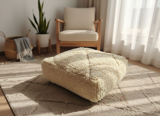 Textured beige wool pouf on a Moroccan rug in a sunlit cozy room