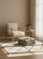 Minimalist reading corner featuring a beige and black Moroccan pouf.