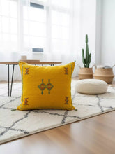 Handmade Tigmmi yellow Berber pillow with traditional Amazigh embroidery on a white rug