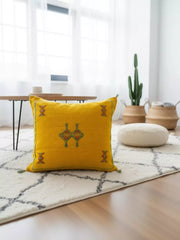 Handmade Tigmmi yellow Berber pillow with traditional Amazigh embroidery on a white rug
