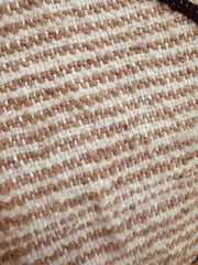 Close-up texture of handwoven beige and cream wool fabric from the pouf