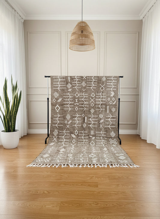 Gray Berber Idya rug displayed on stand with white tribal symbols in a bright room