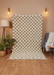 Full view of Timzar beige and cream checkered wool rug hanging against a warm-toned wall.