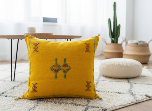Handmade Tigmmi yellow Berber pillow with traditional Amazigh embroidery on a white rug