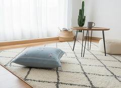 Tanina pillow side view on rug showing detailed Berber motifs and tassels