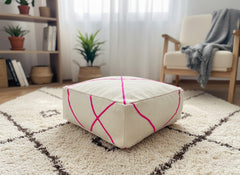 Cream Berber pouf with pink pattern on shag rug