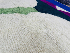 Detail of cream and green handwoven wool fibers on Tissam rug