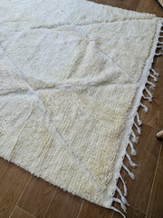 Close-up of handmade wool texture and geometric pattern on beige rug