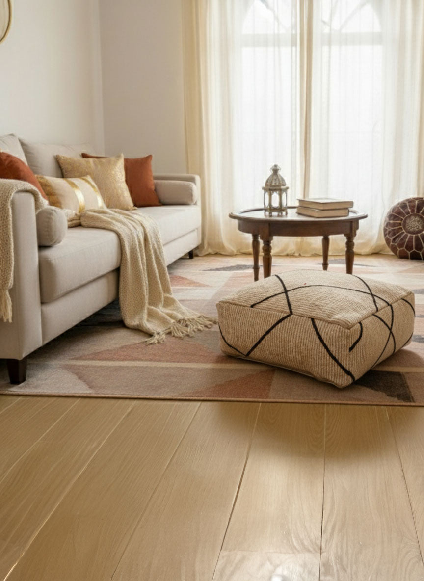Beige Moroccan pouf with black lines placed in a warm modern living room