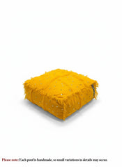 Handwoven yellow Moroccan pouf on white background showing textured details.