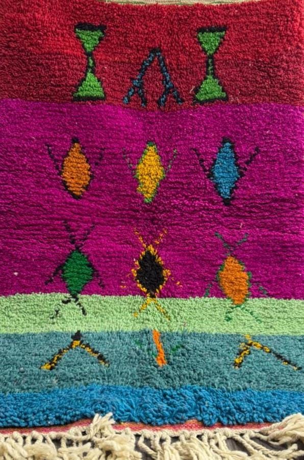 Colorful Moroccan wool rug with geometric motifs and fringe.