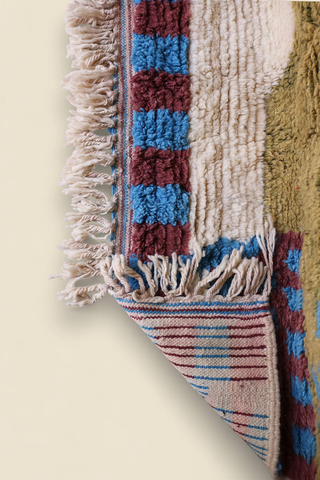 Close-up of Moroccan rug fringe and woven edge with alternating burgundy and blue blocks