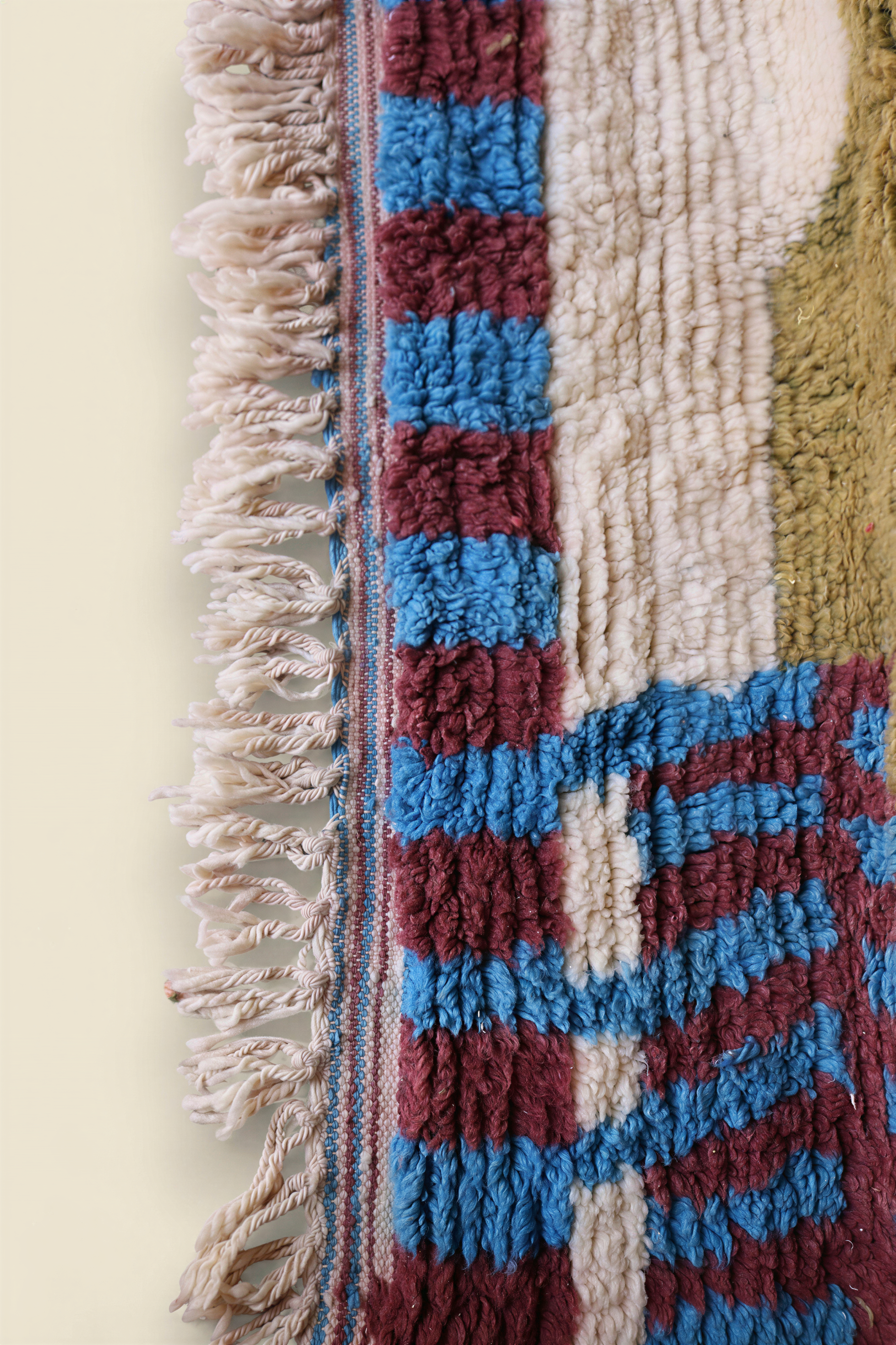 Close-up of Moroccan rug showing olive green and pink wool texture with abstract line patterns