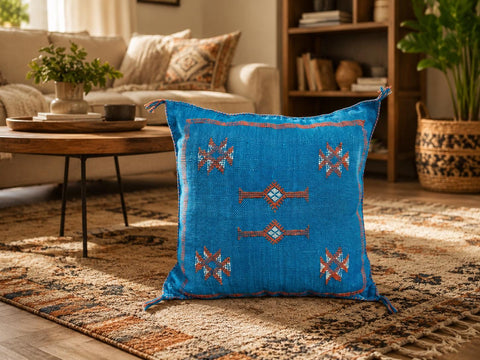 Turquoise Moroccan accent pillow styled on a beige armchair with natural decor.