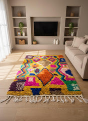 Yellow wool rug with multicolor shapes and tassels on wooden floor