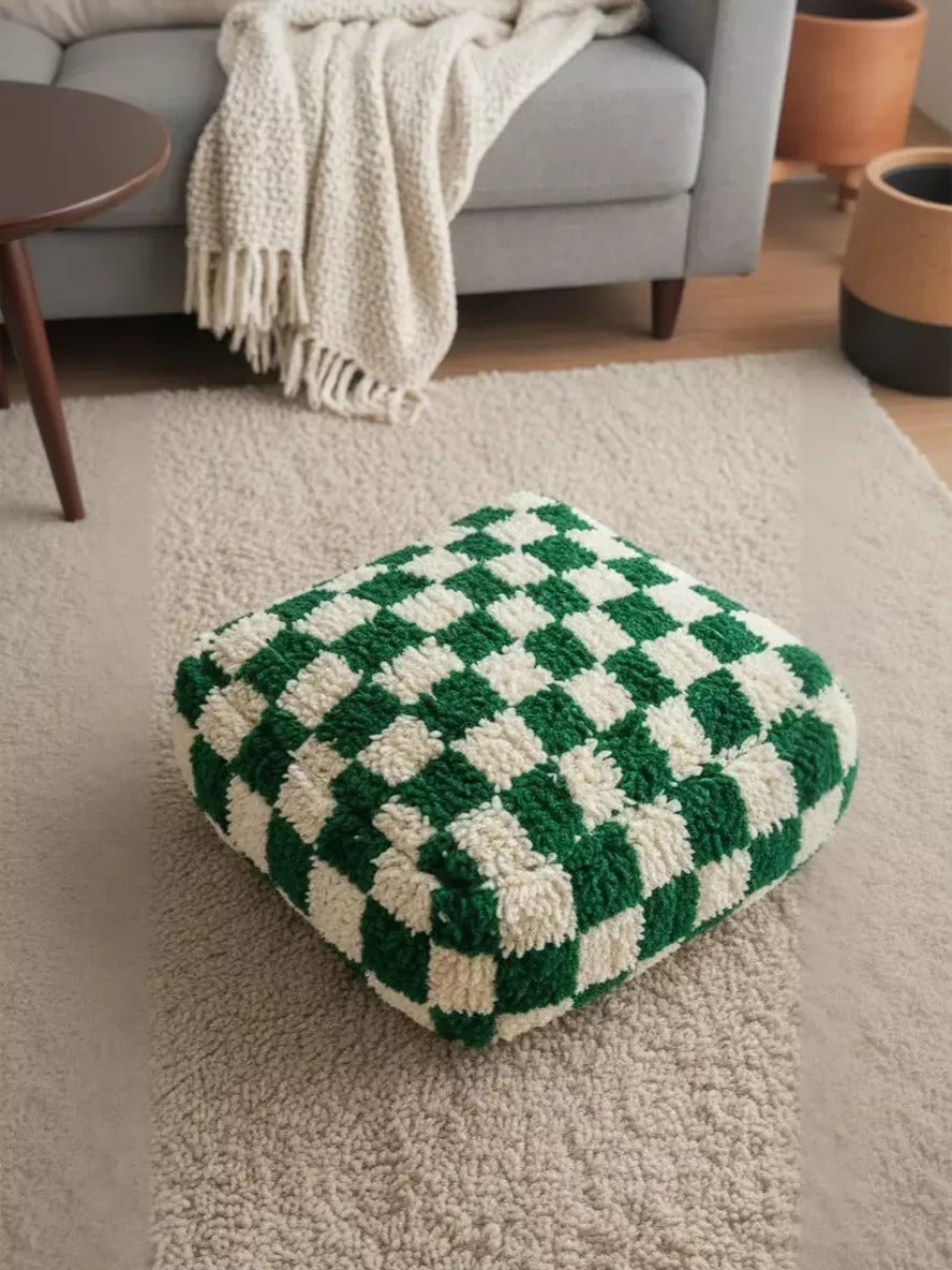 Close-up of the green and cream Elam Berber pouf on a rug.