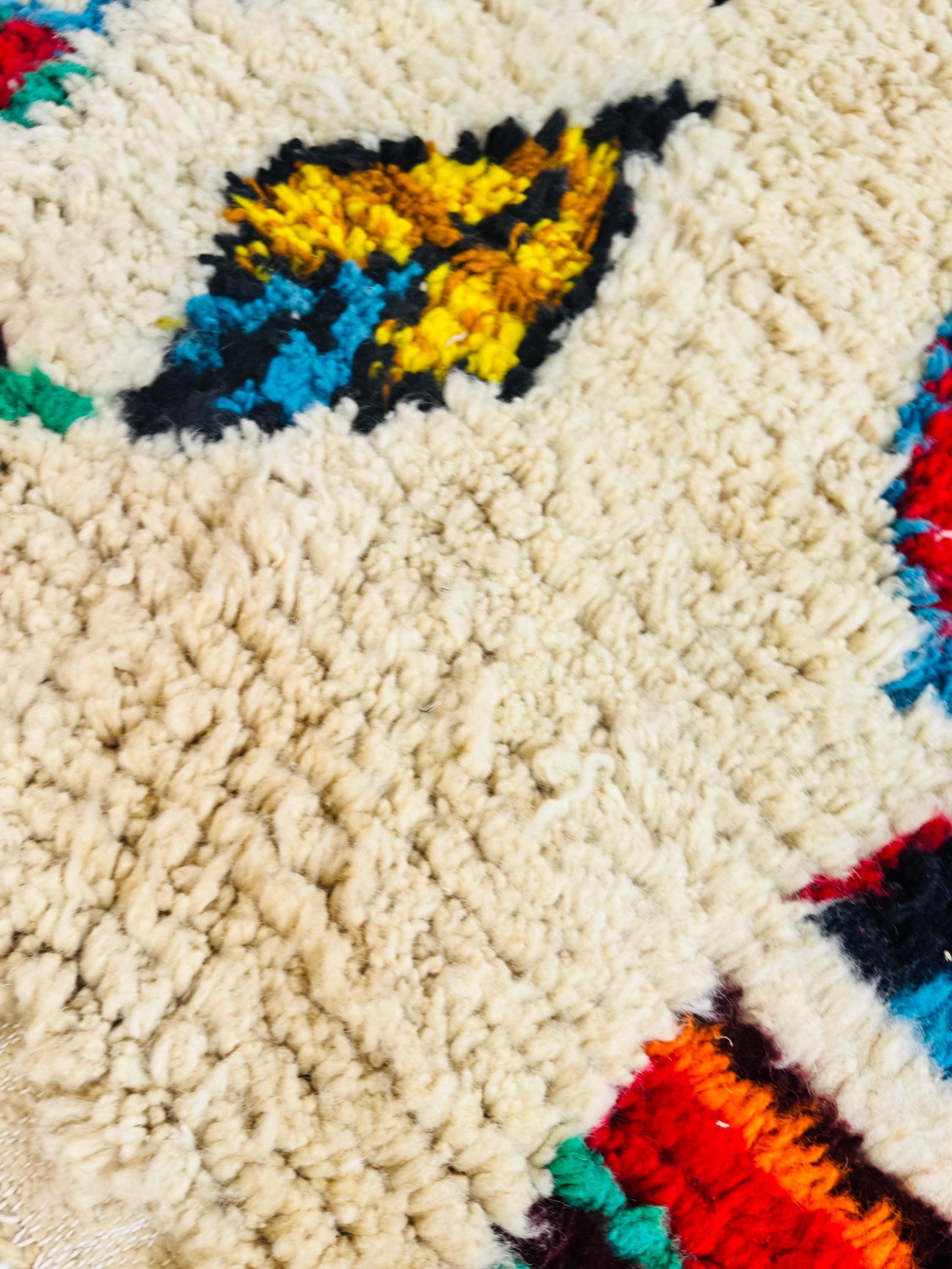 Detailed view of plush wool pile showcasing colorful Berber motifs on a cream background.