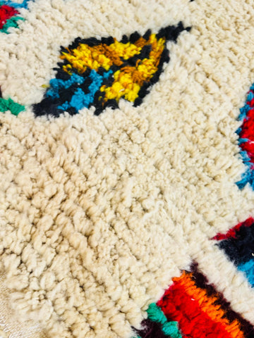 Detailed view of plush wool pile showcasing colorful Berber motifs on a cream background.