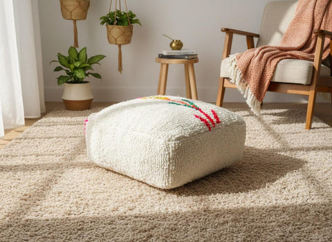 Ivory Moroccan wool pouf styled in a cozy living room