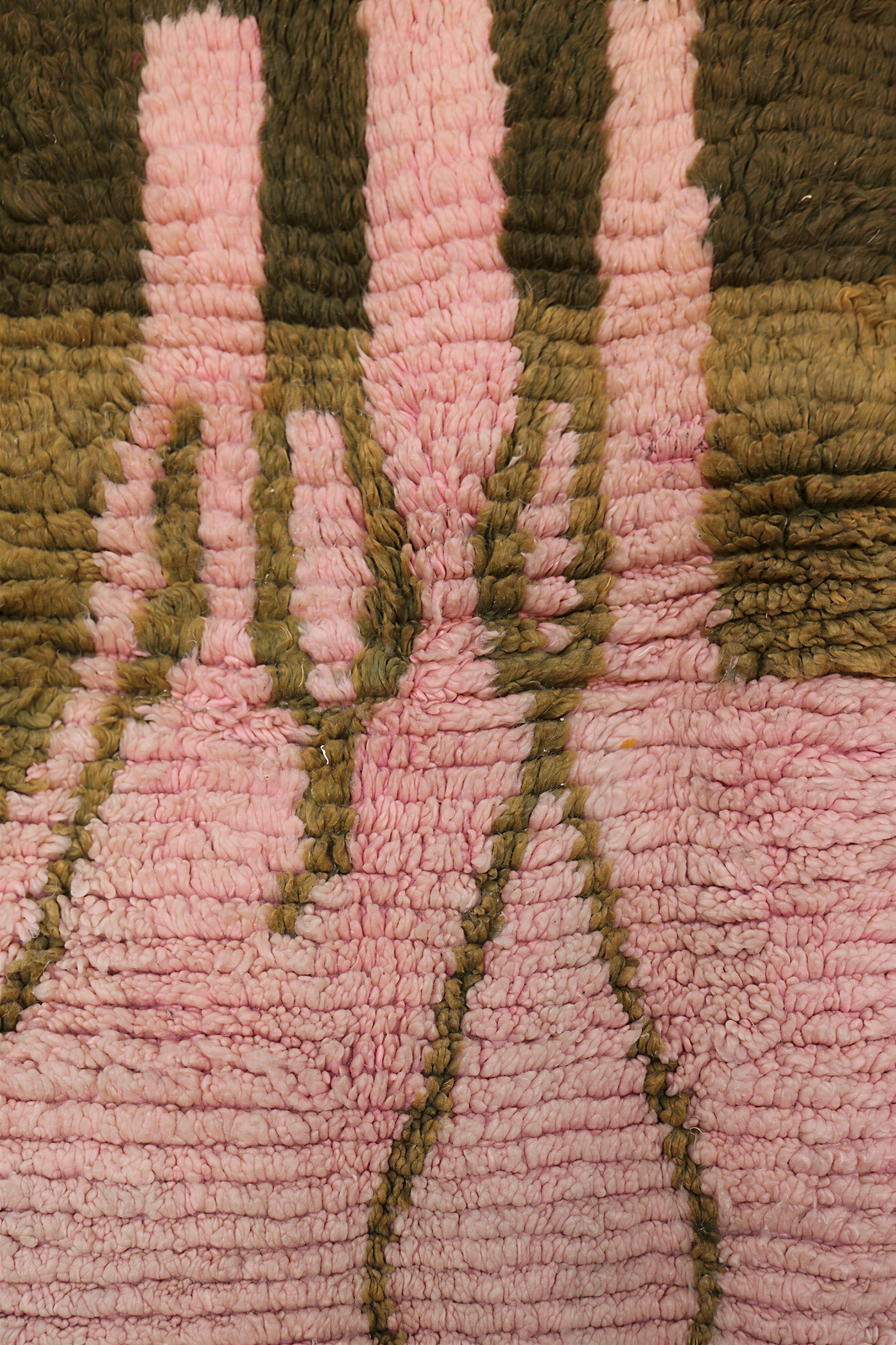 Close-up of Moroccan rug top design with vertical pink shapes outlined in olive green wool