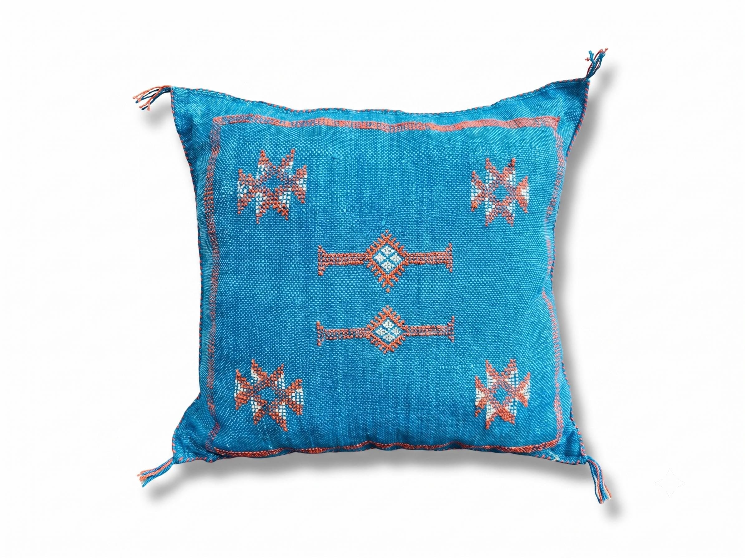 Turquoise Moroccan cactus silk pillow cover with traditional geometric embroidery on white background.