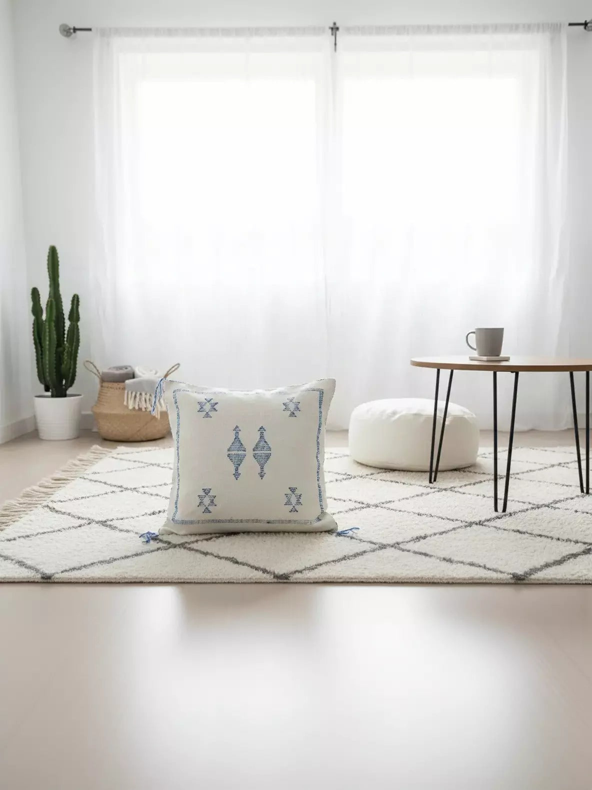 Handwoven Moroccan Tilya Berber pillow in cream and blue with tribal pattern on rug