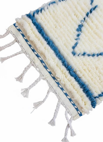 Close-up of blue border and tassels on ivory Berber rug