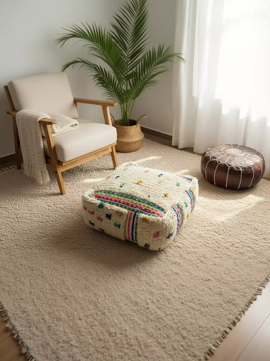 Handmade Berber Adnen pouf with colorful dots on a neutral rug