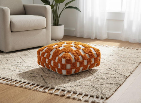 Orange Moroccan wool pouf on neutral rug in bright living room